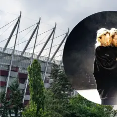 Quebonafide koncert na Stadionie Narodowym. Artysta w czarnym swetrze, z mikrofonem i telefonem w dłoni, na tle sceny.
