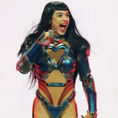 Katy Perry w futurystycznym stroju z sercami na scenie w Krakowie, z otwartymi ustami i błyszczącymi oczami.