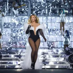 Beyoncé w olśniewającym stroju na scenie, podczas spektakularnego koncertu. Tysiące świateł tworzy magiczną atmosferę.