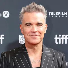 Robbie Williams, znany również jako aktor, w stylowej marynarce w paski na tle logo TIFF.
