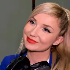 Uśmiechnięta blondynka z kucykiem, słuchawkami na szyi i wyrazistym makijażem. Czy to właśnie tak ma na imię Cleo?