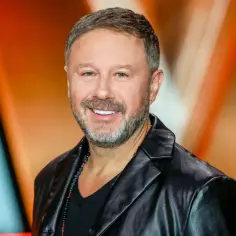 Uśmiechnięty Andrzej Piaseczny w skórzanej kurtce, jakby pozował do zdjęcia z żoną.