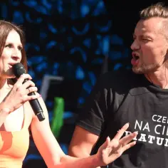 Sylwia Grzeszczak i Liber na scenie, wokalistka śpiewa do mikrofonu, a raper w koszulce z napisem "Czekałem na Ciebie Piątunio" energicznie gestykuluje.