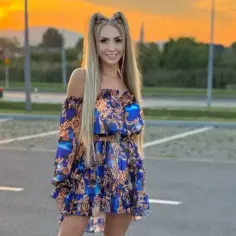 Joanna Narożna w zwiewnej, wzorzystej sukience pozuje na tle zachodzącego słońca.