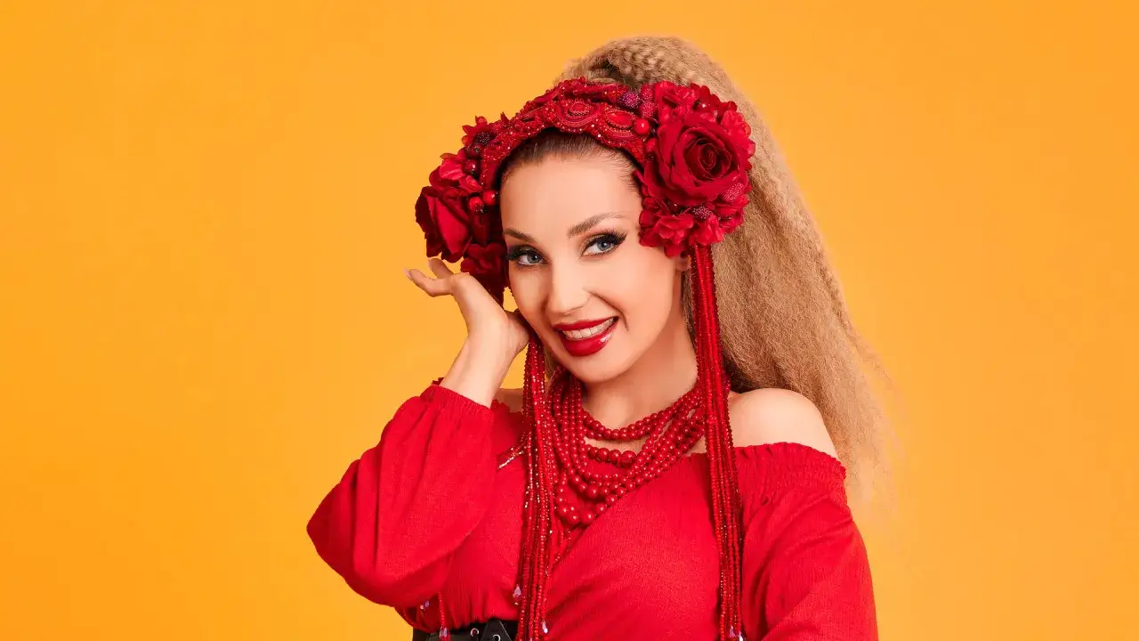 Uśmiechnięta Cleo w czerwonej bluzce i wianku z róż.