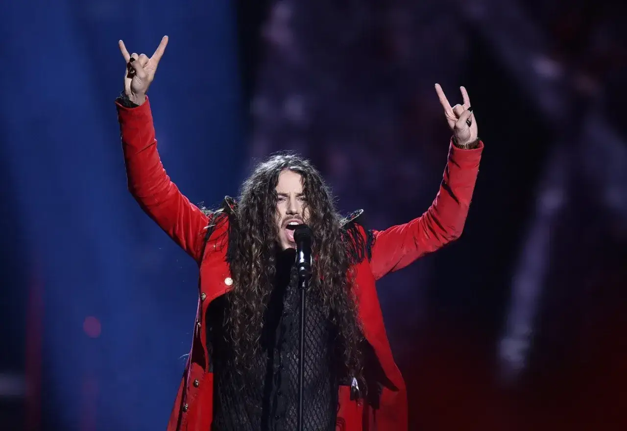 Szpak na Eurowizji, w czerwonym stroju, z uniesionymi rękami i gestem rock'n'rolla, zdobywa serca publiczności.