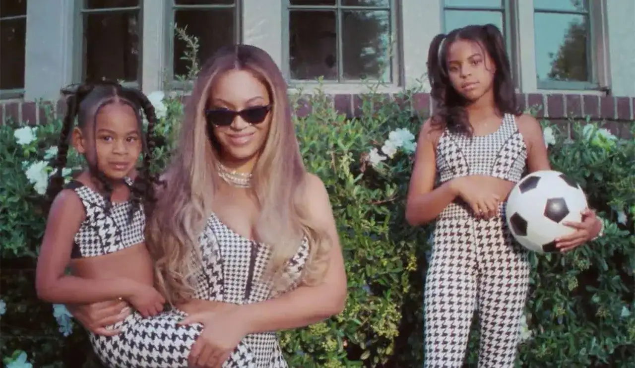 Beyoncé z córkami, Blue Ivy i Rumi, w identycznych strojach. Jedna z córek trzyma piłkę nożną.