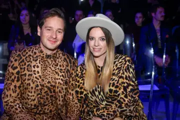 Krzysztof Zalewski i jego żona w identycznych, panterkowych stylizacjach. Uśmiechnięci siedzą obok siebie, ona w kapeluszu.