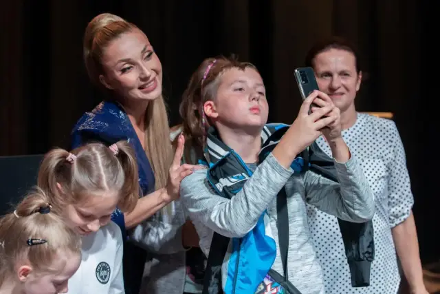 Cleo z dziećmi na scenie. Dziewczynki z kucykami i chłopiec robiący zdjęcie telefonem.